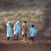 A woman and child on the beach wearing their Seashell changing robes in the colours ocean and sand