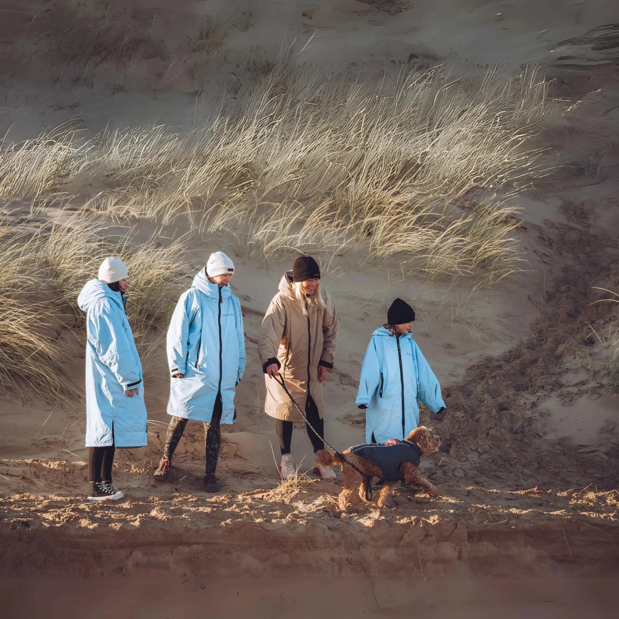 A woman and child on the beach wearing their Seashell changing robes in the colours ocean and sand