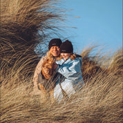 A woman and child on the beach wearing their Seashell changing robes in the colours ocean and sand